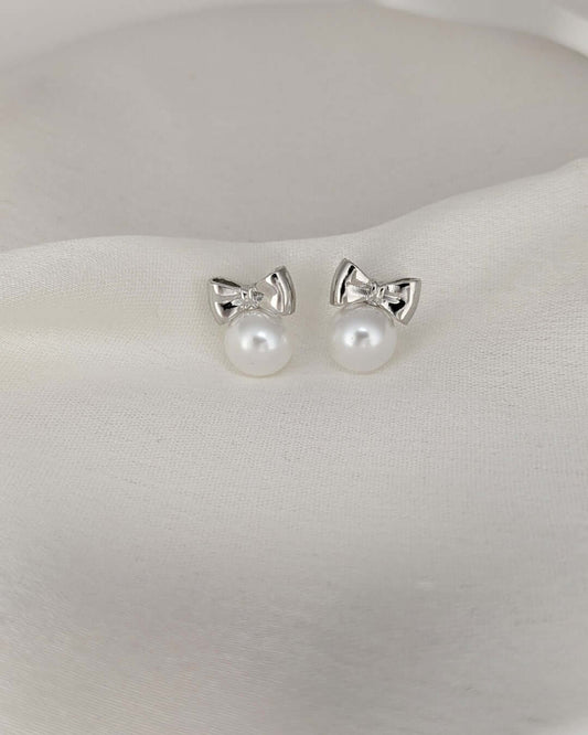 Close-up view of elegant silver bow pearl stud earrings for women