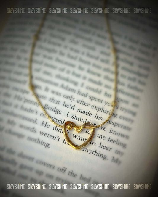 Elegant gold heart knot necklace displayed on an open book with anti tarnish finish